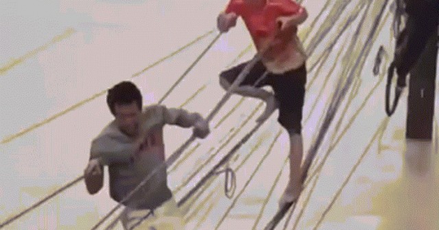 Ba người đàn ông bám dây điện vượt lũ ở Thái Lan